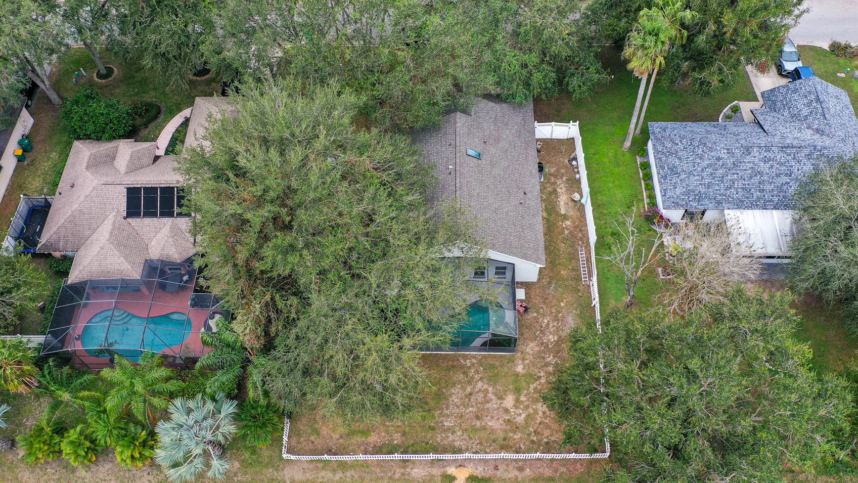 drone shot of home with fence and trees